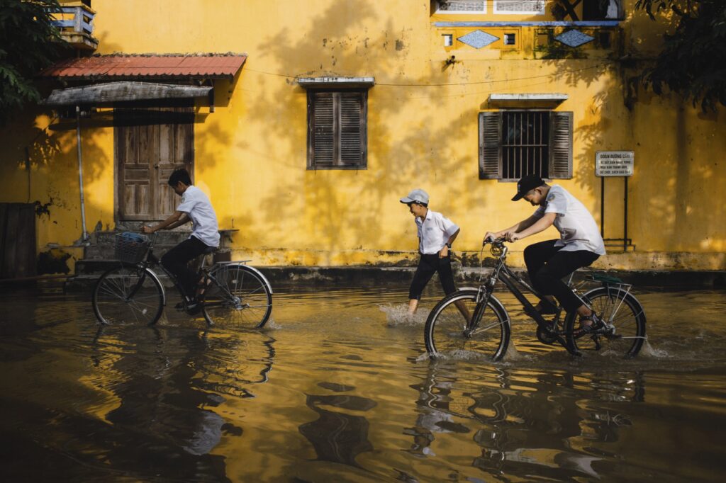 Children coming from school in rain in bicycles.