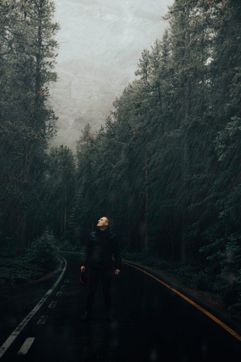 Man standing along in a forest road enjoying rain