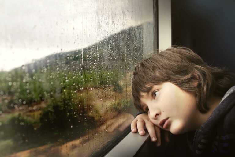 Little boy watching rain through window