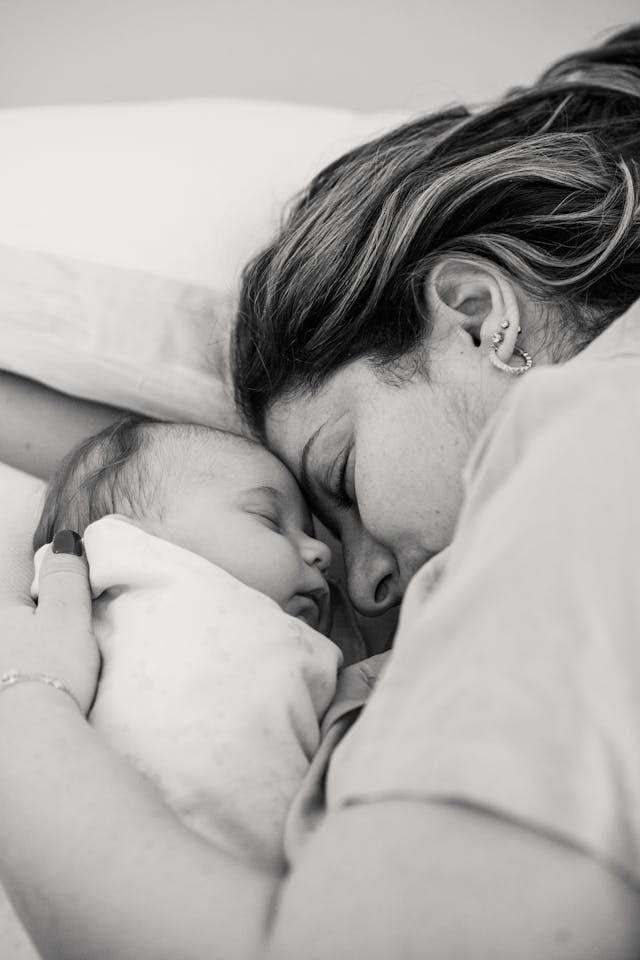 peaceful-young-mother-with-baby-embracing-and-sleeping-on-bed